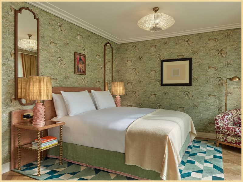 Bed inside a Broadwick Suite with green wallpaper and a Peter Samuelson portrait above.