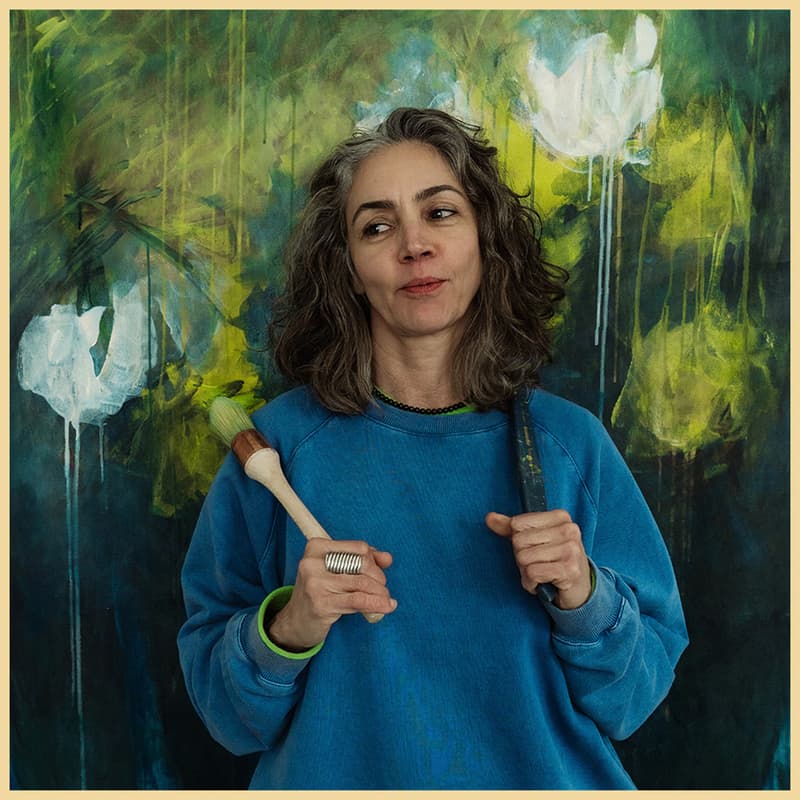 Portrait of Moroccan artist Rita Alaoui in front of a green abstract painting.